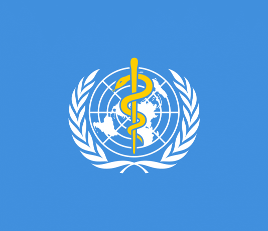 Flag of the World Health Organization (WHO) with a light blue background, the United Nations emblem, and a Rod of Asclepius in the center. Σημαία του Παγκόσμιου Οργανισμού Υγείας (ΠΟΥ) με γαλάζιο φόντο, το έμβλημα του ΟΗΕ και ένα ραβδί του Ασκληπιού στο κέντρο. (GR)