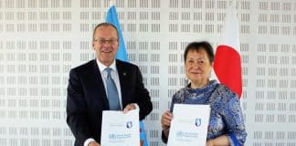 A man and a woman in an official setting holding documents.