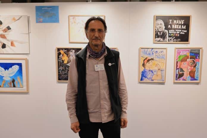 Doros Polykarpou standing in front of a Human Rights exhibit at the European Parliament