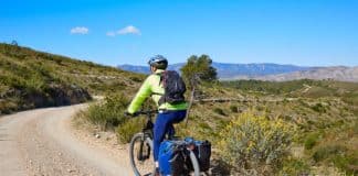 Cyclist with carry-bags on long-distance route. Cycling Tourism is growing.