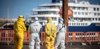 Workers in hazmat suits waiting at docks