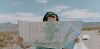 person leaning against a car reading a map