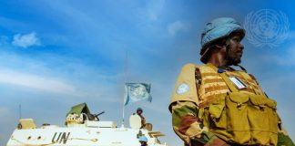 Les missions de maintien de la paix face à la désinformation casques bleus devant un char portant les couleurs de l'ONU