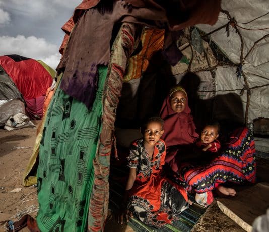 Une mère et ses enfants posent pour une photo dans leur abri temporaire dans un camp pour personnes déplacées. Somalie 2022