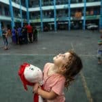 Aya, une fillette de 5 ans, serrant sa poupée pour apaiser sa peur, regarde le ciel de Gaza rempli d'avions de guerre depuis l'intérieur d'une école de l'UNRWA dans la bande de Gaza.