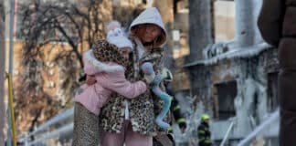 Une mère et sa fille passent devant un bâtiment industriel fortement endommagé à Kiev après une attaque nocturne.