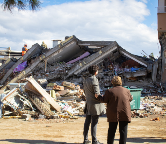 A man and woman look at a collapsed building in Islahyia, Türkiye, on 7 February 2023