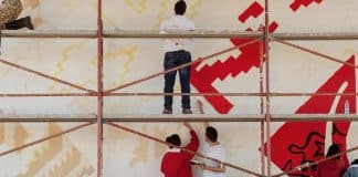 In foto, dei giovani dipingono un muro