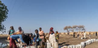 Adulti e bambini sfollati fanno la fila per raccogliere l'acqua da una pompa alimentata a energia solare installata dal UNDP nel campo profughi di Abu Al-Naja, nella città di Gedaref, nello Stato di Gedaref, a circa 400 chilometri a sud-est di Khartoum.