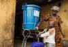 Una madre lava le mani al bambino con acqua trattata con cloro proveniente da un secchio fornito alla famiglia dalla Croce Rossa Internazionale