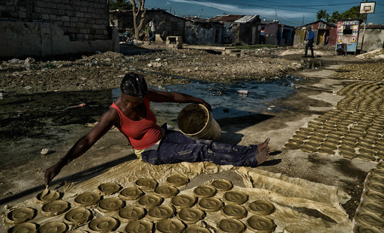 Mulher prepara bolos de barro, discos de barro, manteiga e sal que se tornaram um símbolo da pobreza extrema e fome no Haiti.