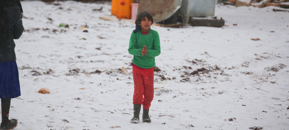 Uma criança caminha na neve em um assentamento informal que continua recebendo famílias recém-deslocadas do sul de Idlib e das províncias rurais de Alepo, no noroeste da Síria.