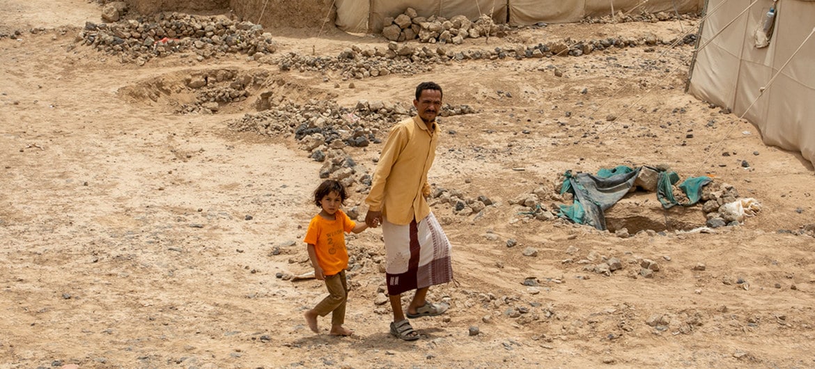 Pai e filho caminham por um campo de deslocados internos perto da cidade de Marib, no Iêmen