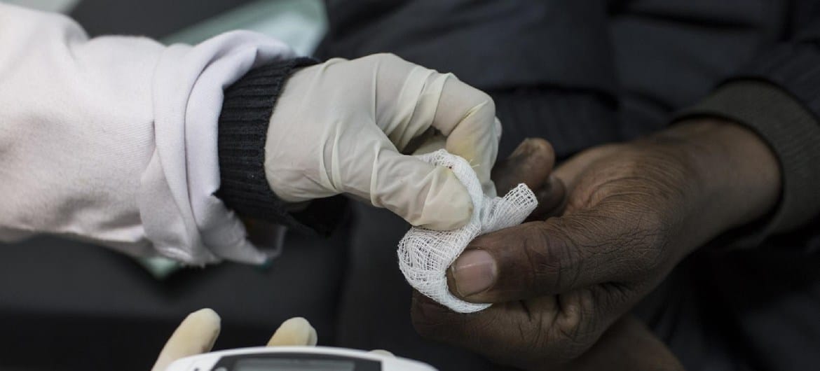 Um oficial de saúde conduz um teste de diabetes na África