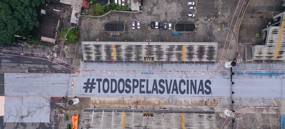 Pintura da mensagem #TodosPelasVacinas na passarela do Anhembi.