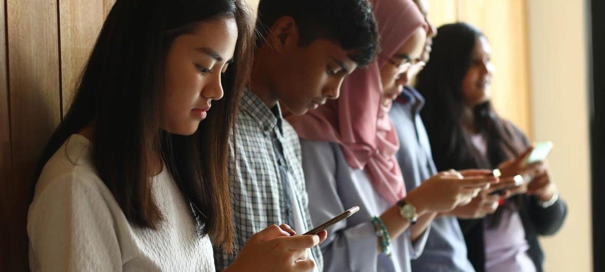Jovens na Malásia usando seus celulares