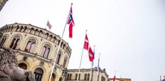 En byggnad i bakgrunden och nordiska flaggor i förgrunden