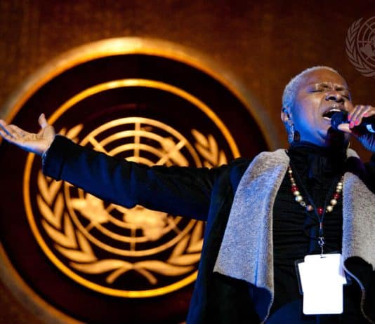 En man som sjunger på en scen med FNs logo i bakgrunden