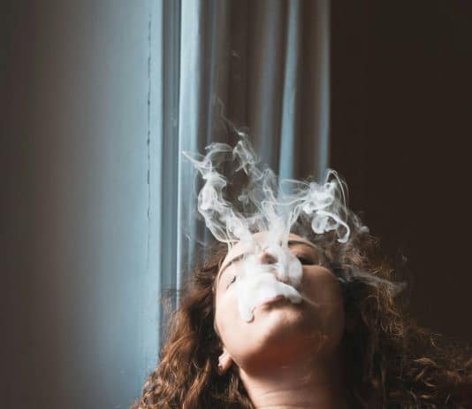 En kvinna som röker en e-cigarett, delvis täckt av rök