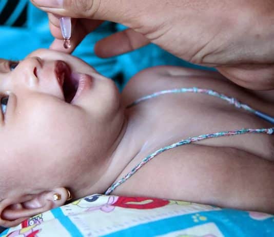 En baby som får flytande vaccin genom munnen